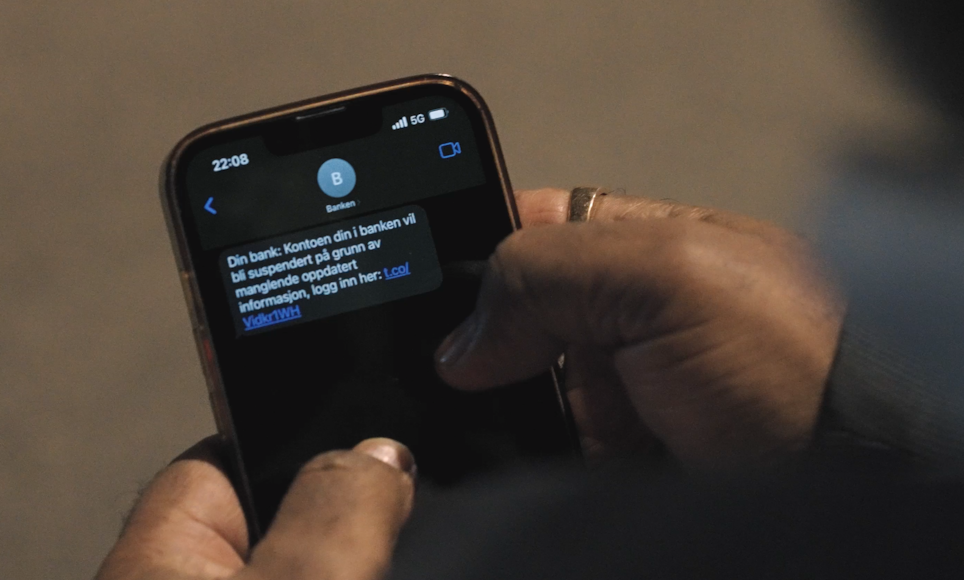 En som holder telefonen sin og leser en SMS-svindel.